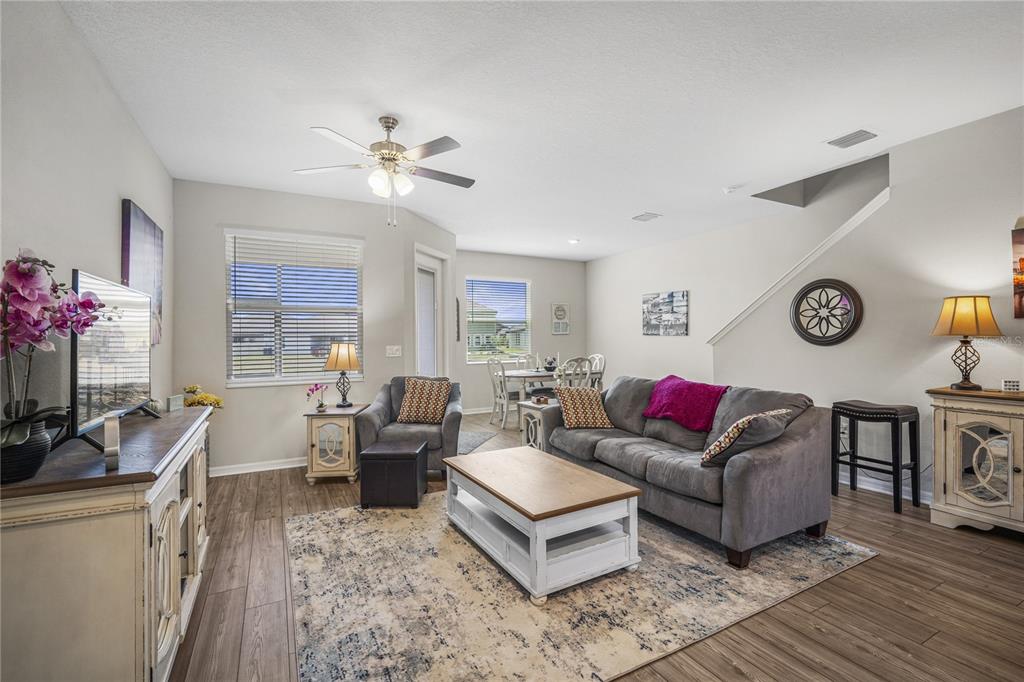 A living room features a gray sofa, a wooden coffee table, and wood-look flooring — 11240 CAY SPRUCE WAY, SAN ANTONIO, FL