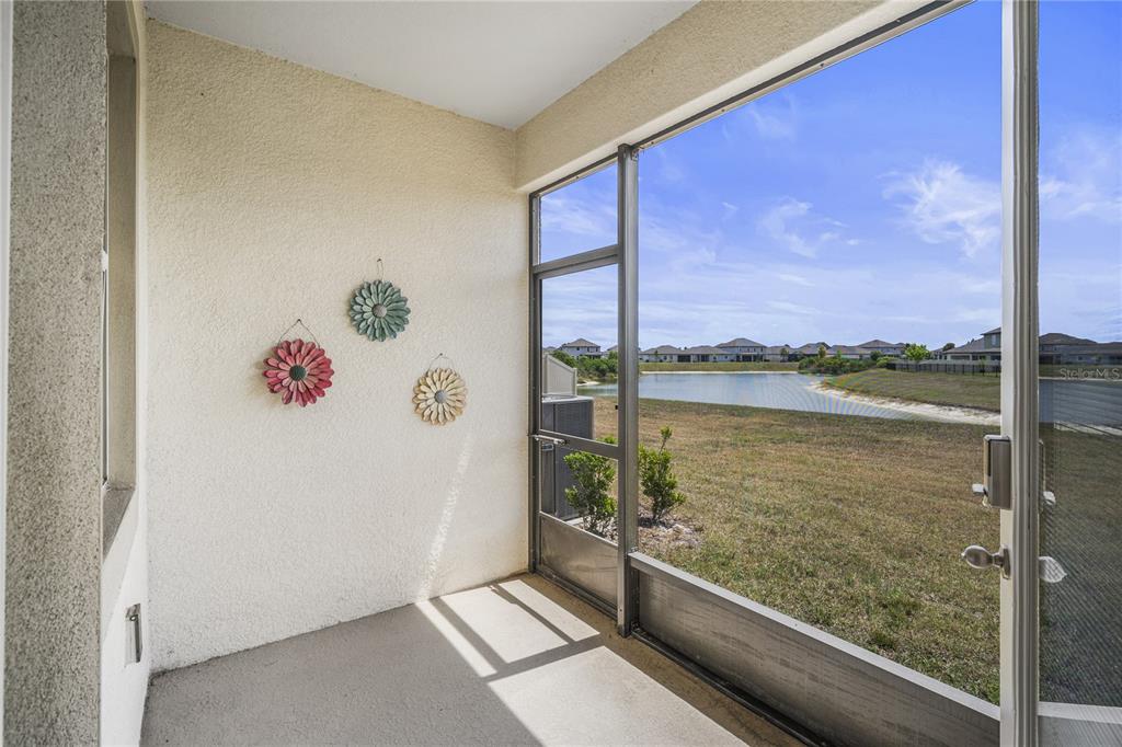 A screened-in porch with a concrete floor overlooks a pond and residential neighborhood — 11240 CAY SPRUCE WAY, SAN ANTONIO, FL