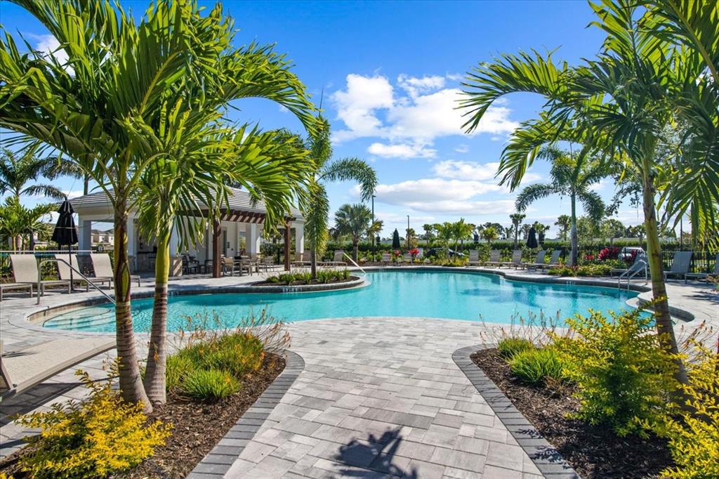 A swimming pool with a paved deck, lounge chairs, and palm trees under a blue sky — 5756 HAVEN TERRACE, NOKOMIS, FL