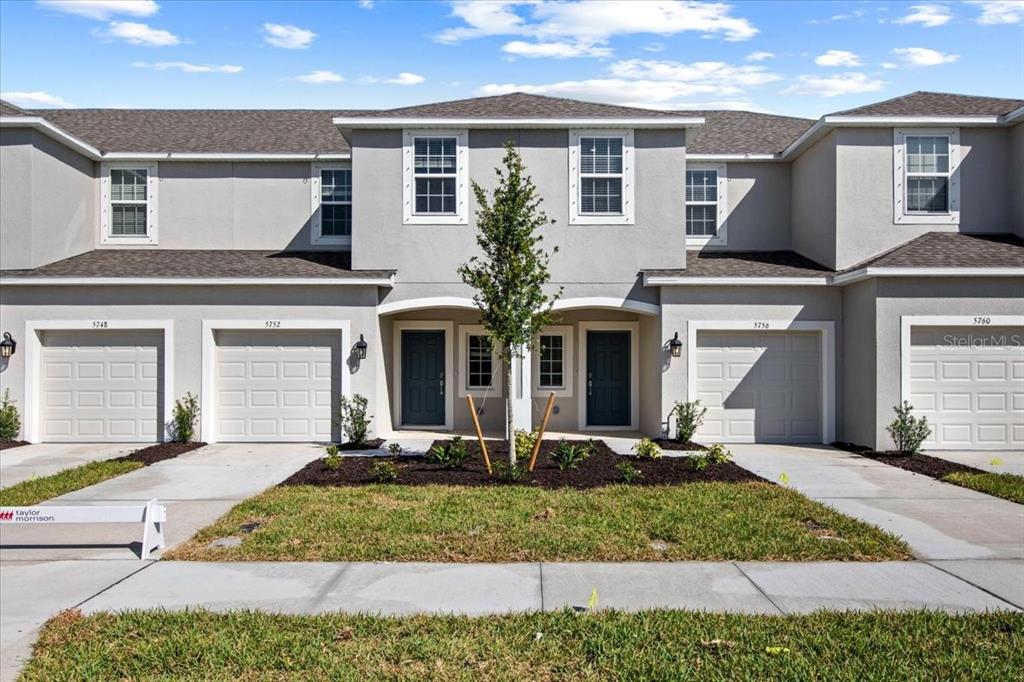A row of modern townhouses features gray stucco exteriors, attached garages, and a central tree — 5756 HAVEN TERRACE, NOKOMIS, FL