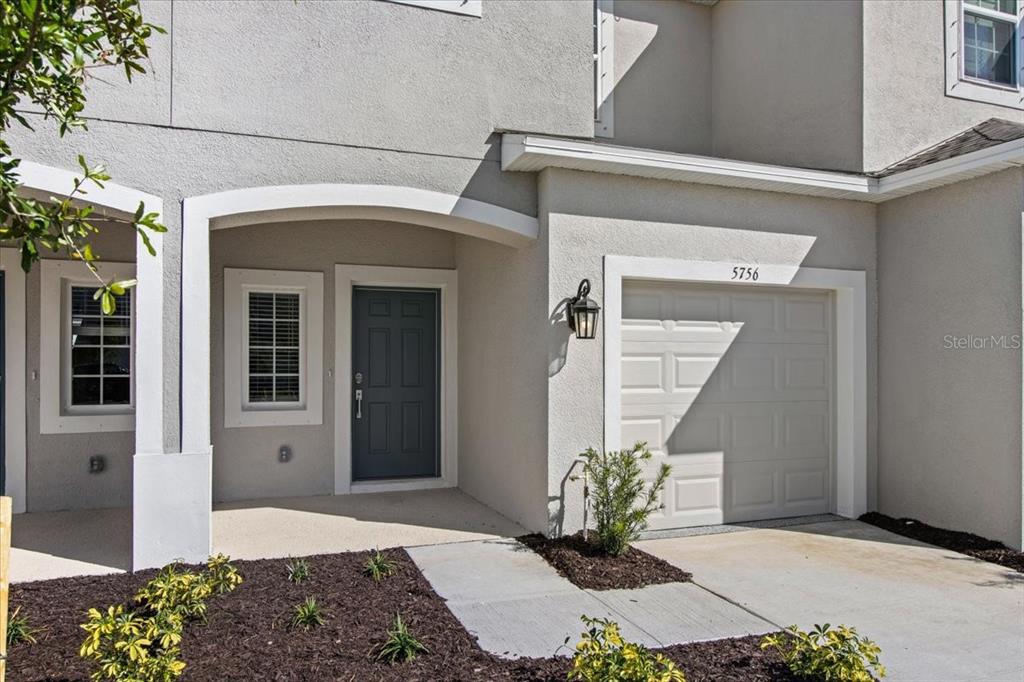 The exterior of a two-story townhouse features a gray front door, a garage, and landscaping — 5756 HAVEN TERRACE, NOKOMIS, FL