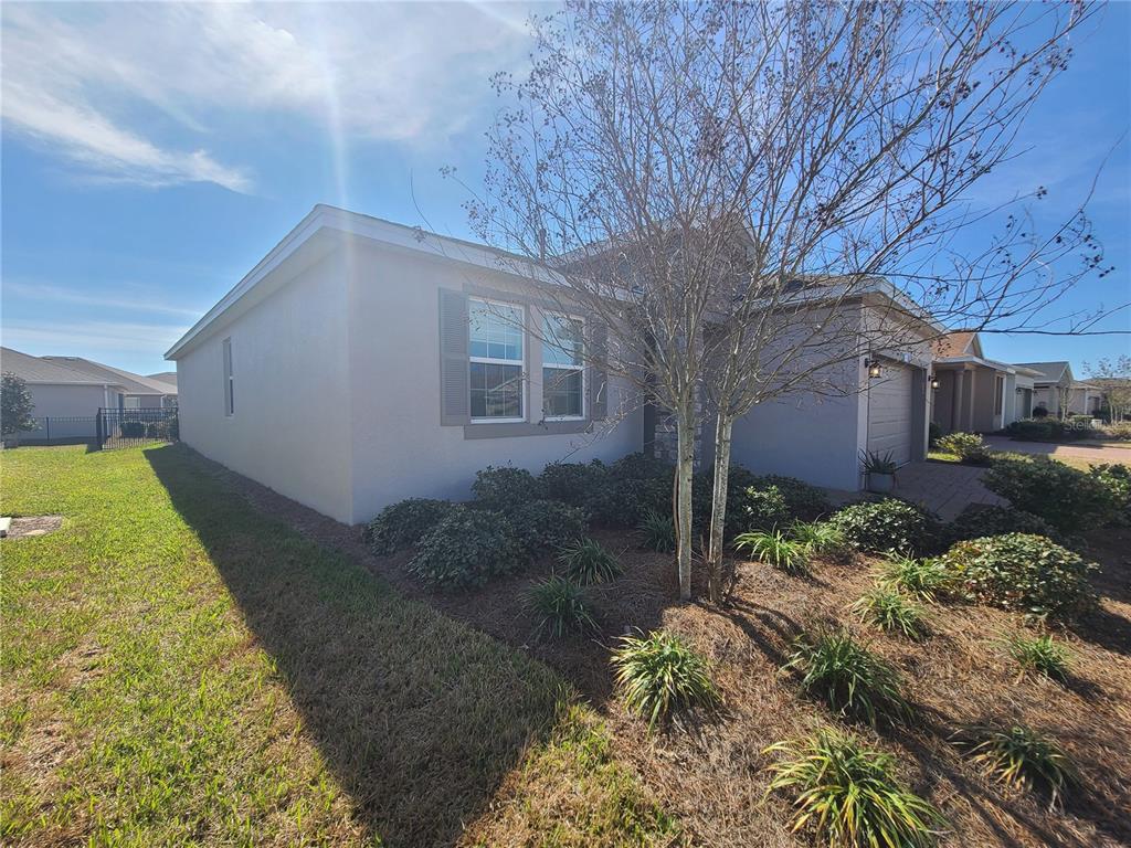 A single-story house with a beige stucco exterior, a front-facing garage, and a landscaped yard — 5380 NW 43RD LANE ROAD, OCALA, FL