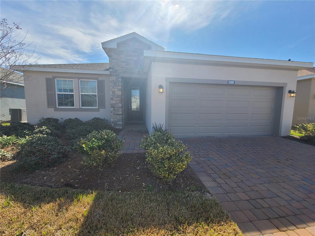 A single-story house features a stone-accented entryway, a two-car garage, and a paved driveway — 5380 NW 43RD LANE ROAD, OCALA, FL