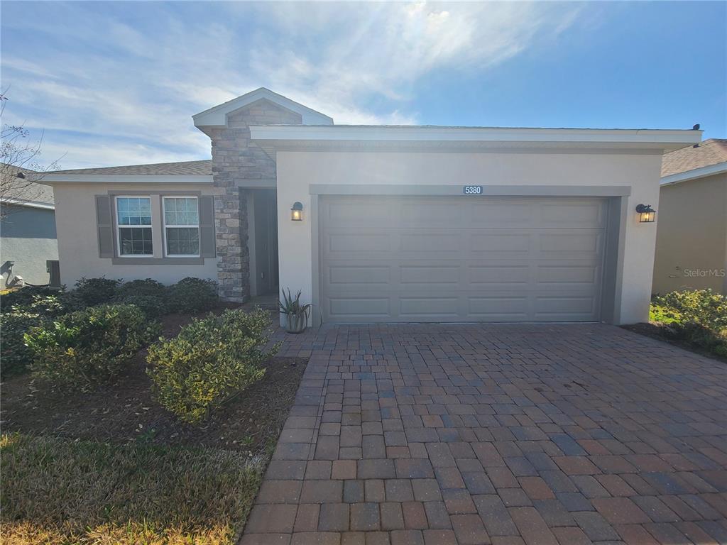 A single-story house features a stone-accented entryway, a two-car garage, and a paved driveway — 5380 NW 43RD LANE ROAD, OCALA, FL