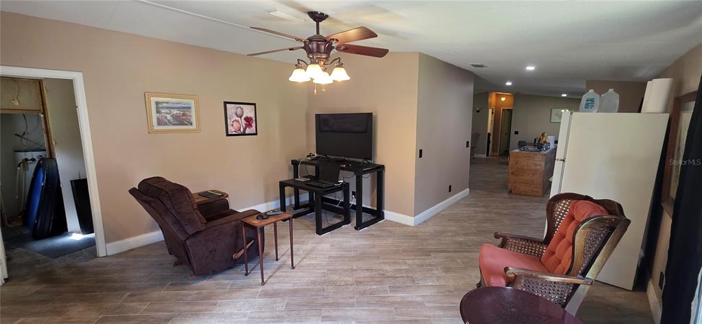 A living room features light-colored tile flooring, a ceiling fan, and a television on a stand — 11736 CR 675W, WEBSTER, FL