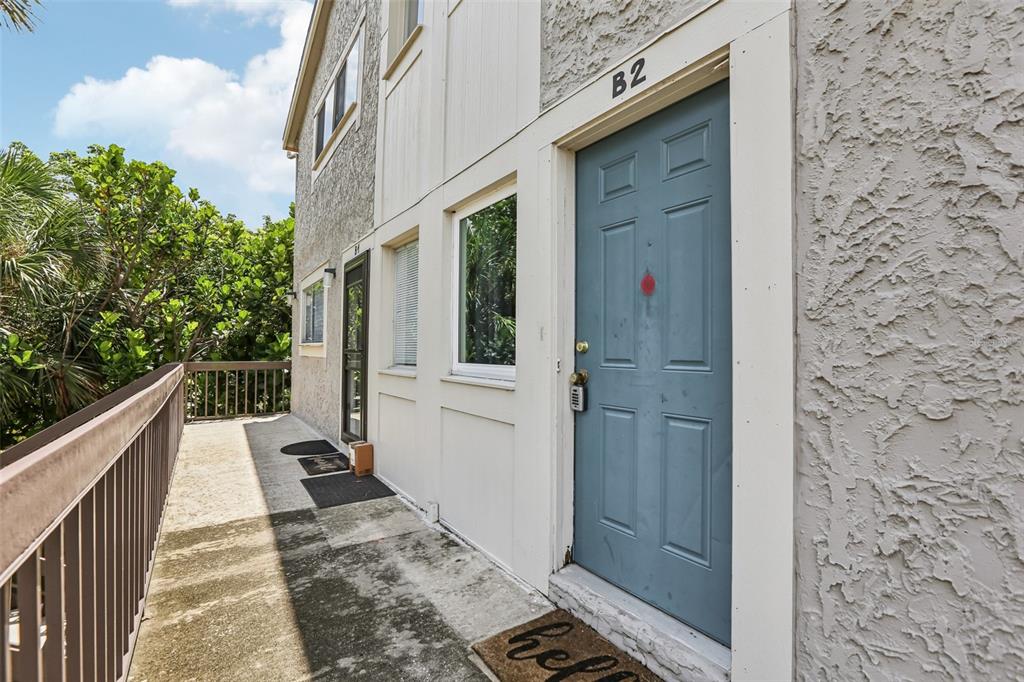 An exterior view of a building balcony with a blue door marked B2 — 6325 NEWTOWN CIRCLE UNIT 25B2, TAMPA, FL