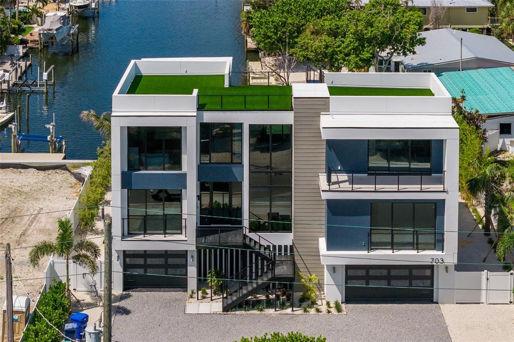 An aerial view of a modern three-story house with flat roofs and artificial turf terraces — 703 S BAY BOULEVARD, ANNA MARIA, FL