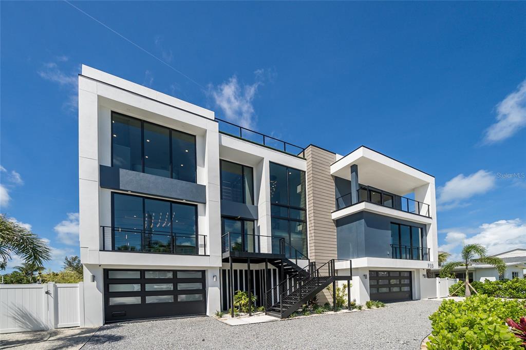 A modern three-story house with a gravel driveway, two garages, and exterior balconies — 703 S BAY BOULEVARD, ANNA MARIA, FL