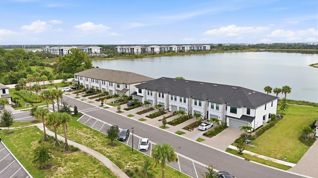 An aerial view shows a row of townhouses situated along a lake with parking spaces — 6340 SILVERSTAR DRIVE, SARASOTA, FL