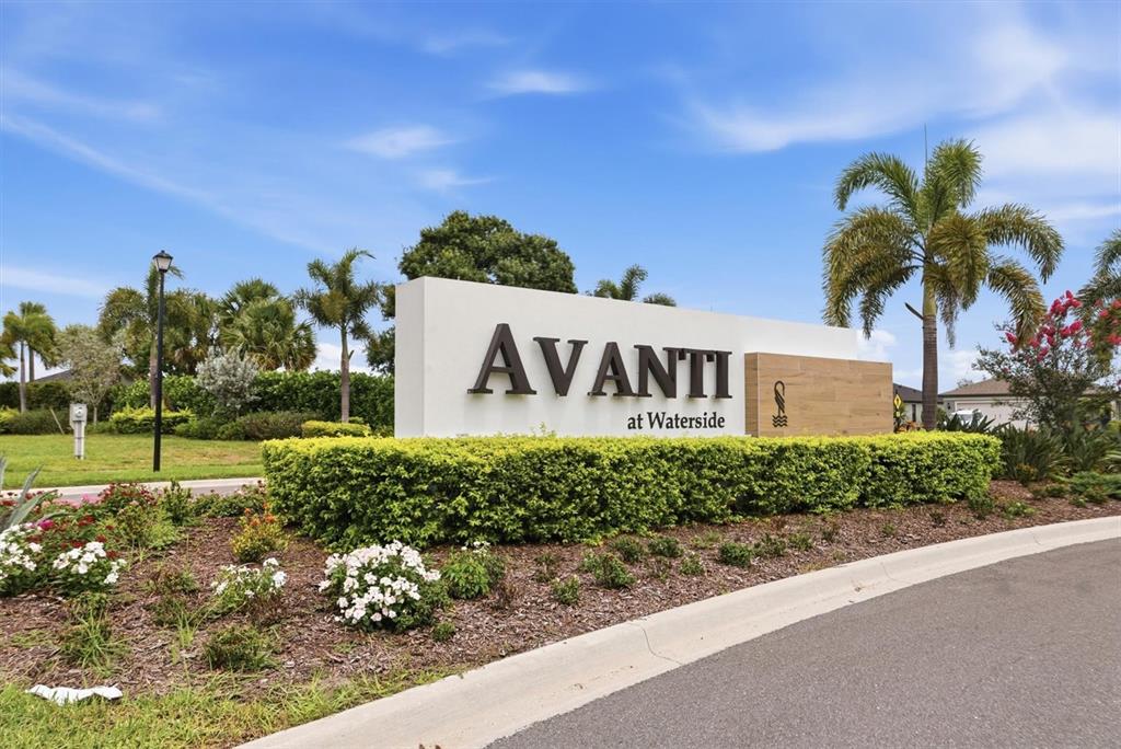A white monument sign for Avanti at Waterside stands in a landscaped garden area — 6340 SILVERSTAR DRIVE, SARASOTA, FL