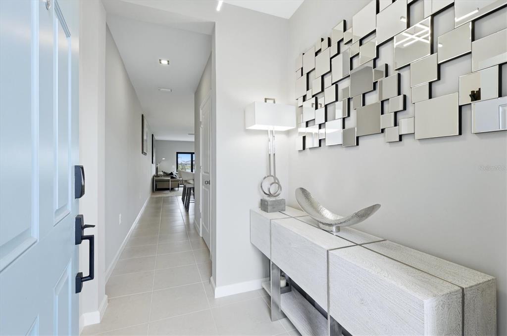 A bright entryway features light tile flooring, a modern console table, and a geometric mirror — 6340 SILVERSTAR DRIVE, SARASOTA, FL