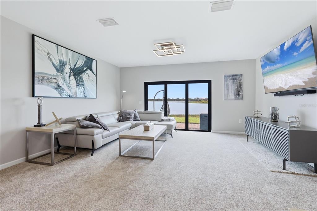 A living room features a gray sectional sofa, a television, and sliding doors overlooking water — 6340 SILVERSTAR DRIVE, SARASOTA, FL
