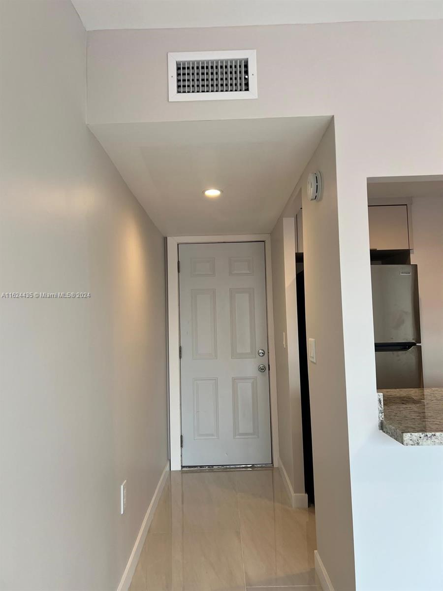 A hallway with light-colored tile flooring leads to a white door under a recessed light — 6580 W Flagler St # 309, Miami FL 33144, MIAMI, FL