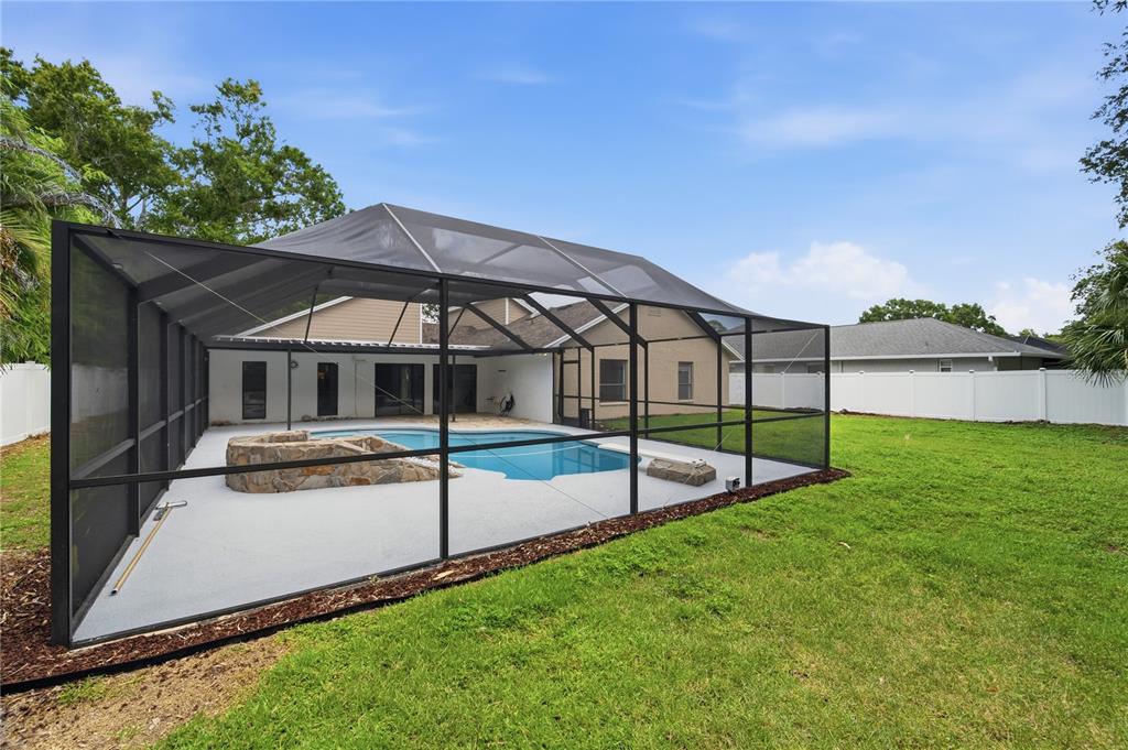 A backyard features a swimming pool enclosed by a black metal screen cage — 14207 ASHBURN PLACE, TAMPA, FL