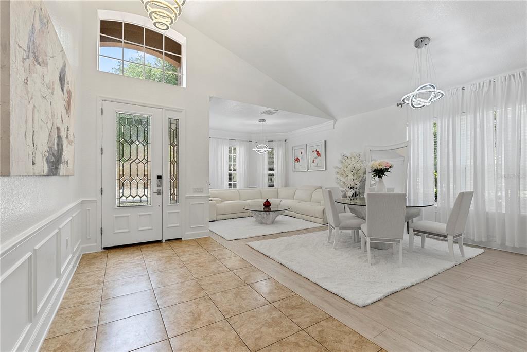A bright, open-concept living and dining area features tiled floors, white walls, and vaulted ceilings — 446 ANESSA ROSE LOOP, OCOEE, FL