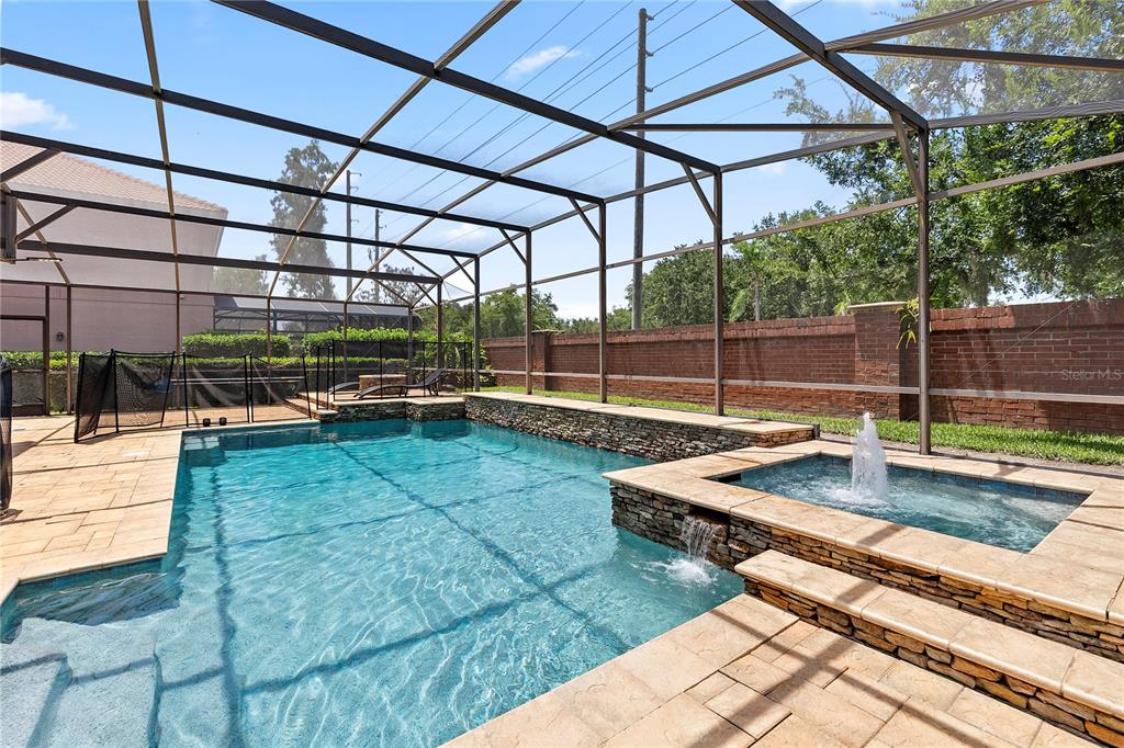 A screened-in swimming pool and spa with stone accents and a brick perimeter wall — 446 ANESSA ROSE LOOP, OCOEE, FL
