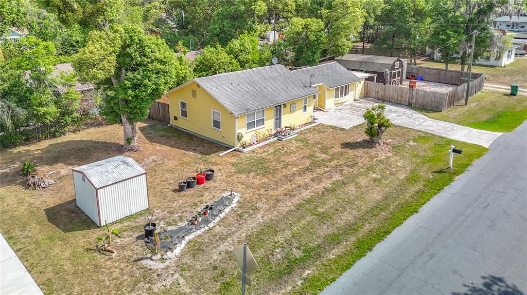 An aerial view of a yellow single-story house with a metal shed and driveway — 38703 9TH AVENUE, ZEPHYRHILLS, FL