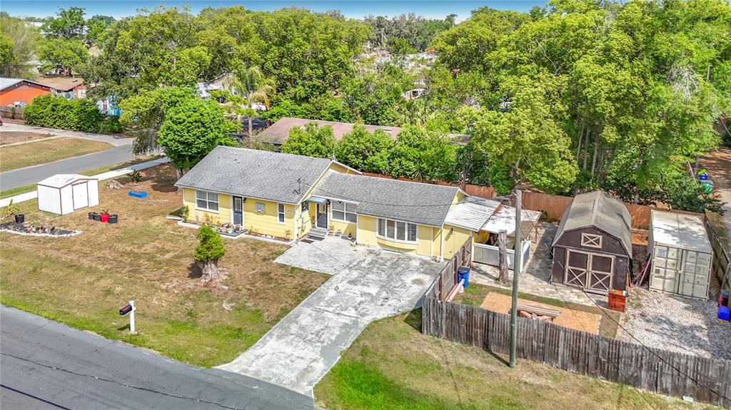 An aerial view of a yellow single-story house with a driveway and two storage sheds — 38703 9TH AVENUE, ZEPHYRHILLS, FL
