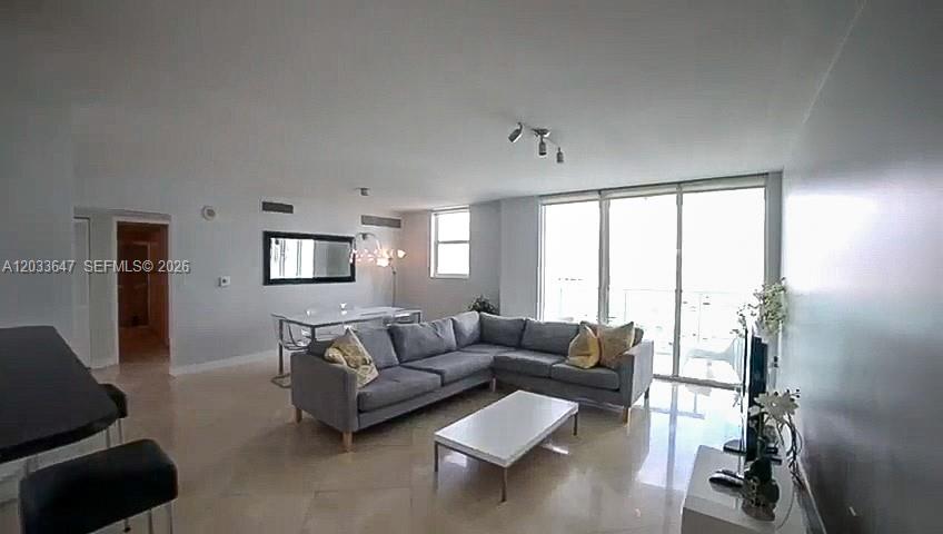 A living room features a gray sectional sofa, a white coffee table, and large sliding doors — 31 SE 5th St # 2001, Miami FL 33131, MIAMI, FL
