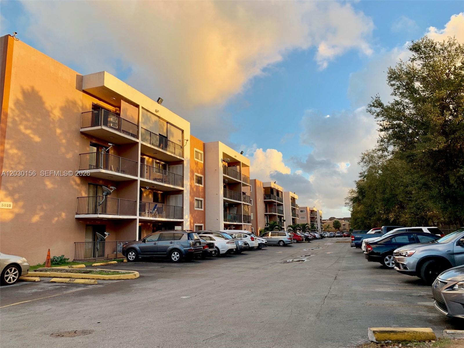 A multi-story apartment building with balconies overlooks a parking lot filled with various cars — 5825 W 25th Ct # 311, Hialeah FL 33016, HIALEAH, FL