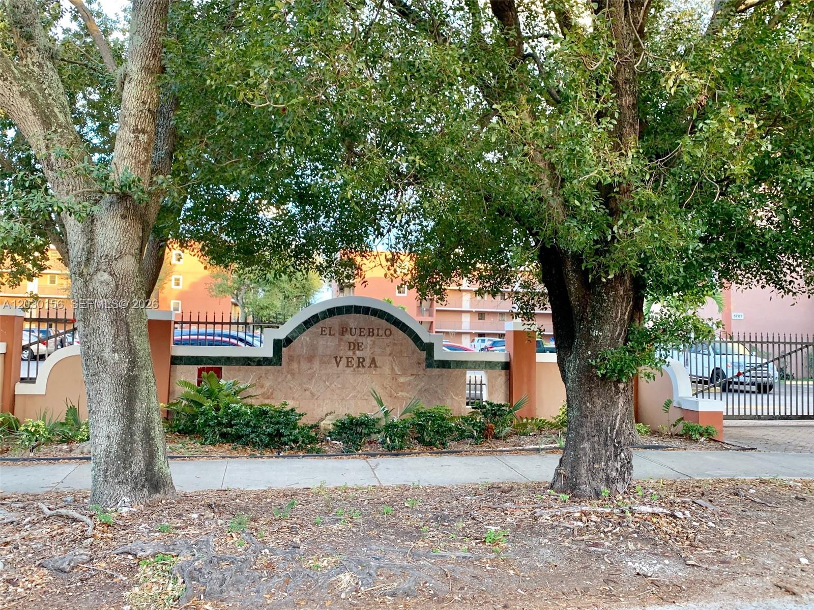 The exterior entrance sign for El Pueblo de Vera is framed by two large trees — 5825 W 25th Ct # 311, Hialeah FL 33016, HIALEAH, FL