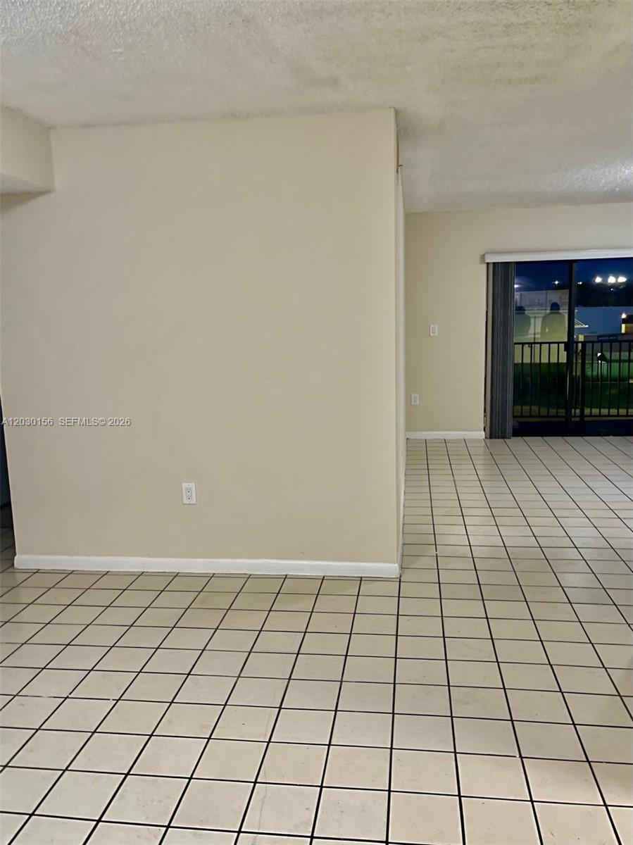 An interior view shows a room with beige walls, white baseboards, and tiled flooring — 5825 W 25th Ct # 311, Hialeah FL 33016, HIALEAH, FL