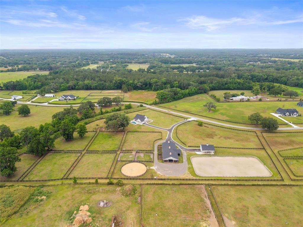 An aerial view shows a rural property with a house, barn, paddocks, and riding arena — 11257 NW 50TH LANE, OCALA, FL