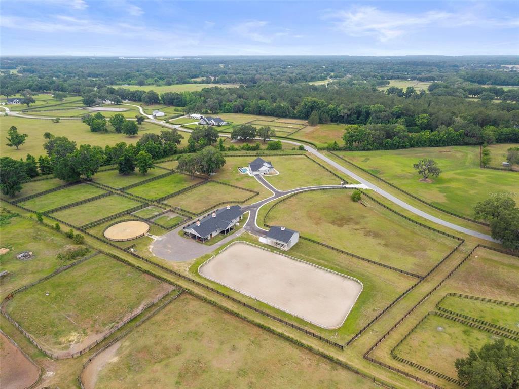 An aerial view shows a rural property with a house, stables, and a riding arena — 11257 NW 50TH LANE, OCALA, FL