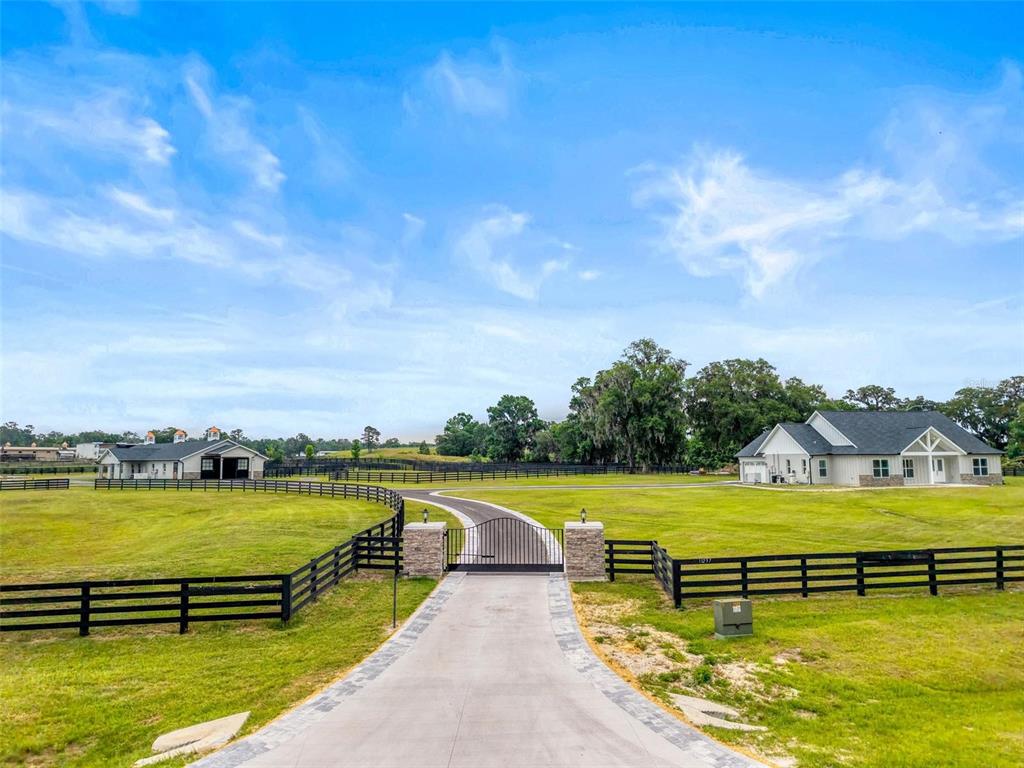 A gated concrete driveway leads to a rural property with a house and a barn — 11257 NW 50TH LANE, OCALA, FL