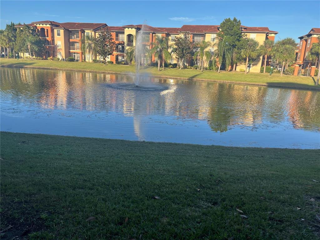 A fountain sprays water in a pond in front of a multi-story apartment building — 5572 METROWEST BOULEVARD UNIT 209, ORLANDO, FL