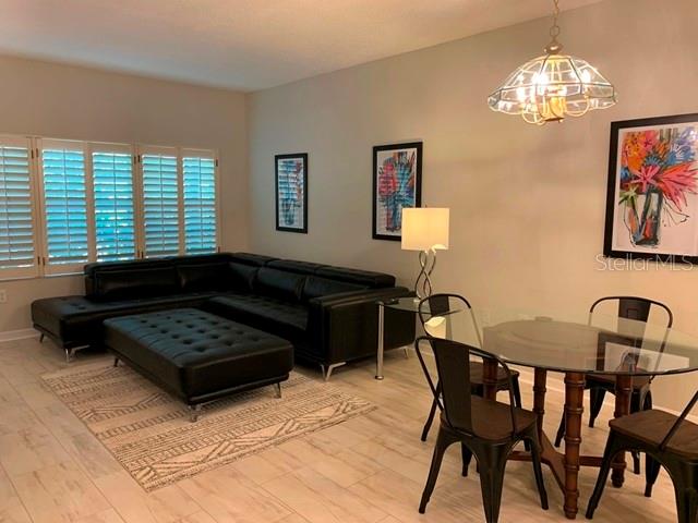 A living and dining area features a black sectional sofa, glass table, and tile flooring — 3401 54TH DRIVE W UNIT 103, BRADENTON, FL