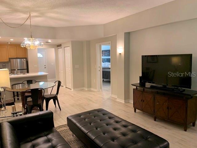 A living room with a television console, leather ottoman, and an adjacent dining area — 3401 54TH DRIVE W UNIT 103, BRADENTON, FL