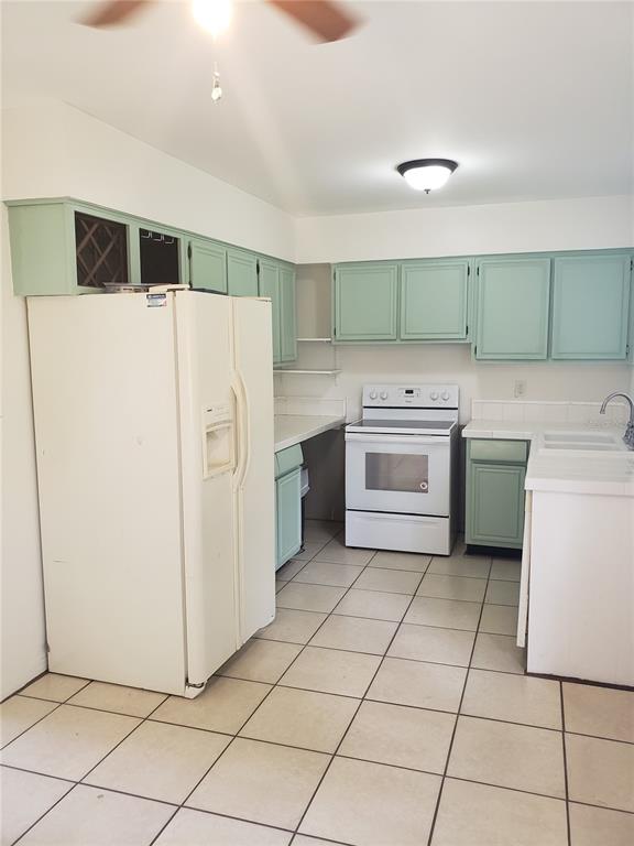 A kitchen features light green cabinets, white appliances, and light-colored tile flooring — 7475 19TH AVENUE N, ST PETERSBURG, FL