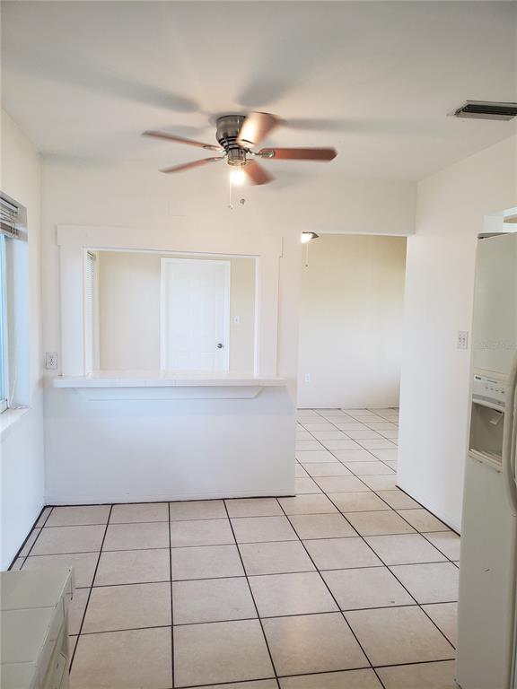 A kitchen with tiled floors, a ceiling fan, and a pass-through window to another room — 7475 19TH AVENUE N, ST PETERSBURG, FL