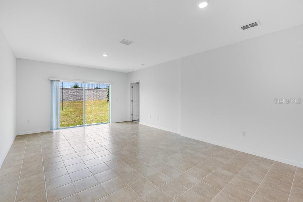 An empty room with light-colored tile flooring, white walls, and a sliding glass door — 13836 SHELLMORE AVENUE, PALMETTO, FL