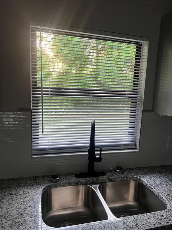 A kitchen sink with a black faucet sits in front of a window with blinds — 1606 NW 20TH COURT, OCALA, FL
