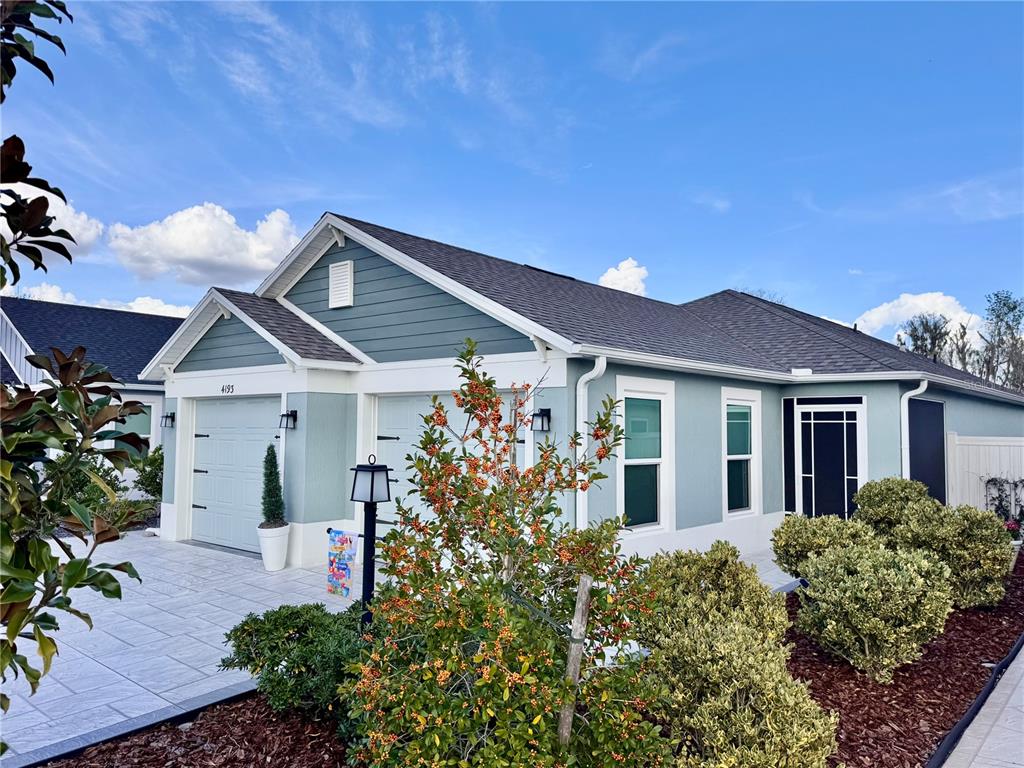 A light blue single-story house features a white garage, dark roof, and landscaped front yard — 4193 SILVANA WAY, THE VILLAGES, FL