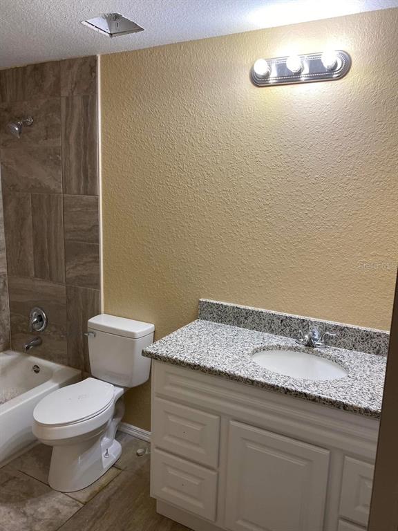 A bathroom featuring a white vanity with a granite countertop, a toilet, and a bathtub — 4300 W HIGHWAY 316, REDDICK, FL