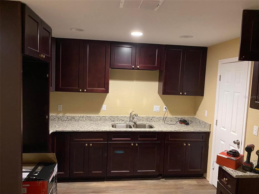 A kitchen features dark wood cabinets, granite countertops, and a double-basin stainless steel sink — 4300 W HIGHWAY 316, REDDICK, FL