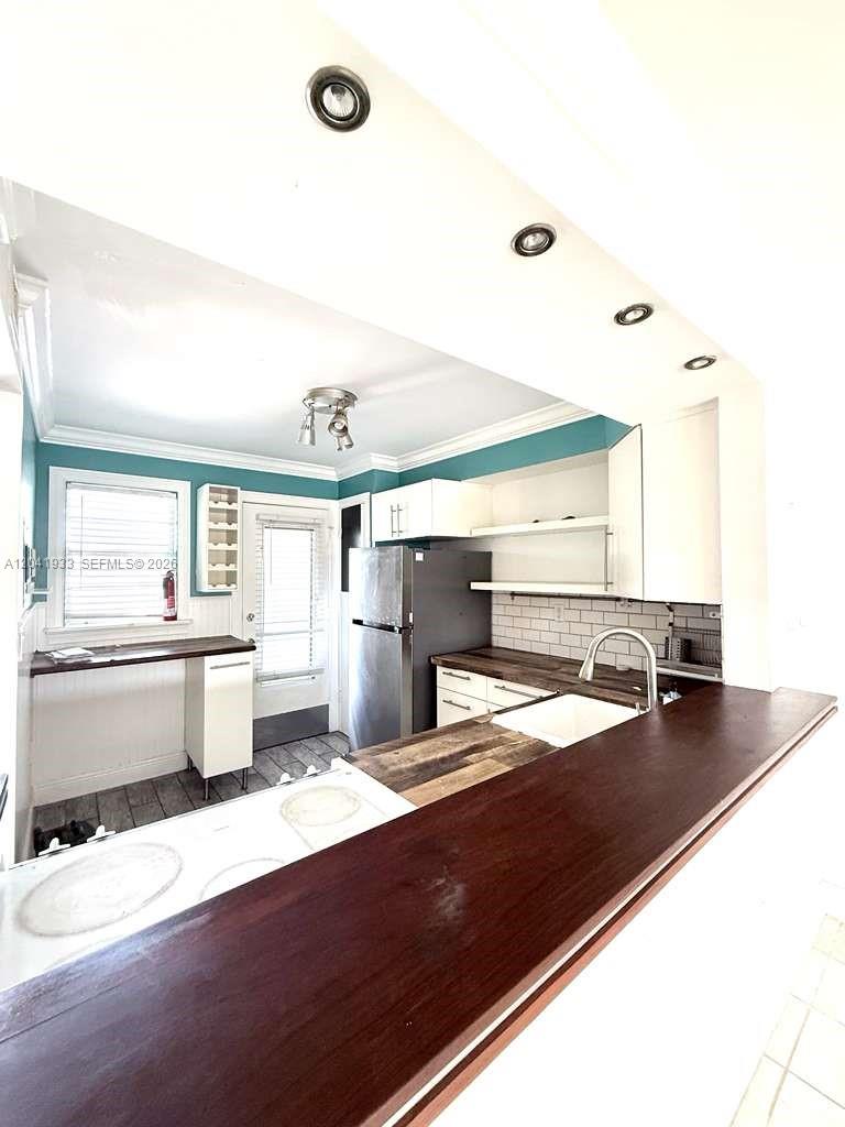 A kitchen features dark wood countertops, white cabinets, a stainless steel refrigerator, and teal walls — 1530 NE 191st St # 340, Miami FL 33179, MIAMI, FL