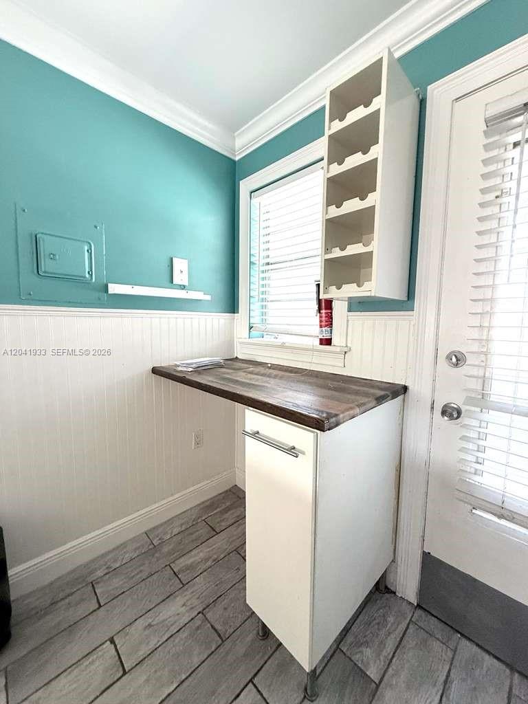 A laundry room features a wood countertop, white cabinetry, and teal walls with wainscoting — 1530 NE 191st St # 340, Miami FL 33179, MIAMI, FL
