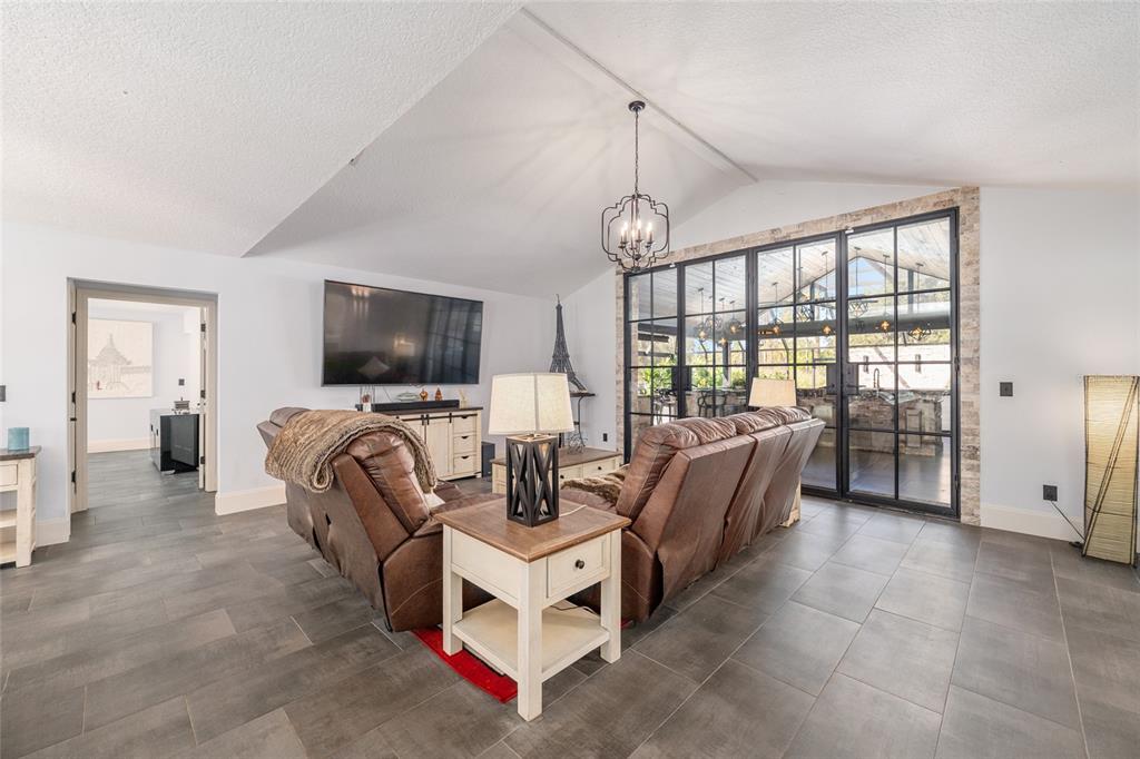 A living room features leather recliners, a vaulted ceiling, and large glass doors to a patio — 10310 GOPHER ROAD, HOWEY IN THE HILLS, FL