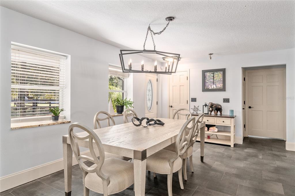 A dining room features a light wood table, six chairs, a chandelier, and tile flooring — 10310 GOPHER ROAD, HOWEY IN THE HILLS, FL