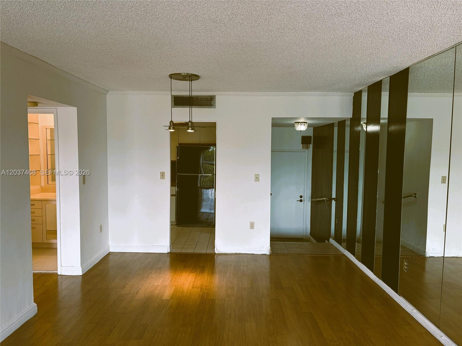 A room with wood flooring, a kitchen doorway, and a mirrored wall — 8775 Park Blvd # 406, Miami FL 33172, MIAMI, FL