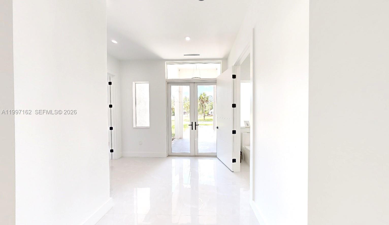 A bright entryway features white walls, polished tile floors, and double glass doors — 3762 32nd AVE SE, Naples FL 34117, NAPLES, FL