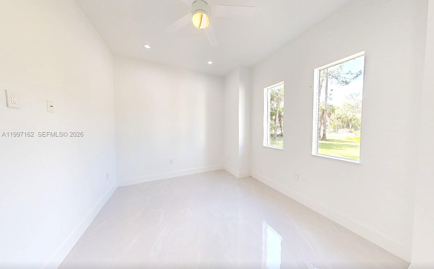 An empty room with white walls, tile flooring, a ceiling fan, and two windows — 3762 32nd AVE SE, Naples FL 34117, NAPLES, FL