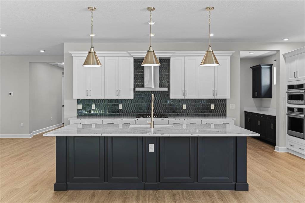 A kitchen features a dark blue island, white upper cabinets, and a dark tiled backsplash — 956 CLUB CRESSWIND DRIVE, LADY LAKE, FL