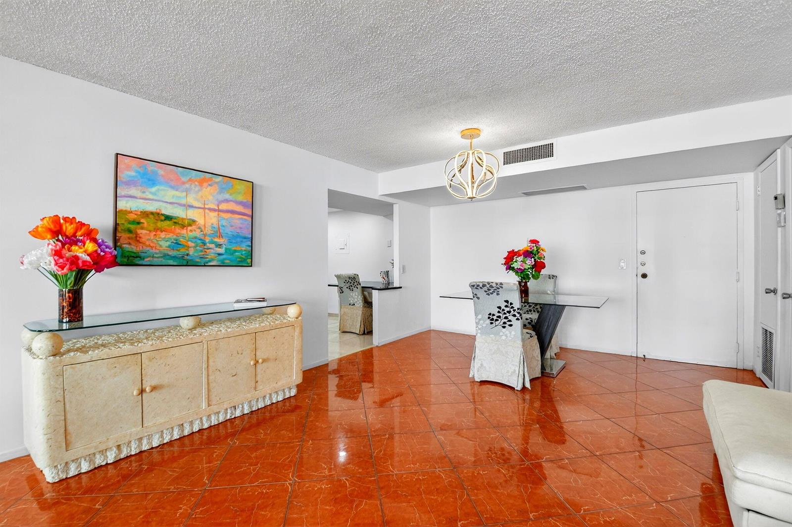 A dining area features orange tile floors, a glass-top table, and a stone sideboard — 3456 S Ocean Boulevard # 1040, Palm Beach FL 33480, PALM BEACH, FL