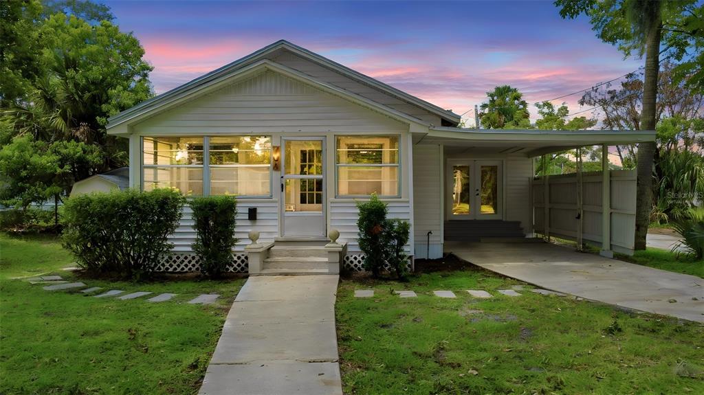 A white single-story house with a front porch, a concrete walkway, and an attached carport — 708 CELERY AVENUE, SANFORD, FL