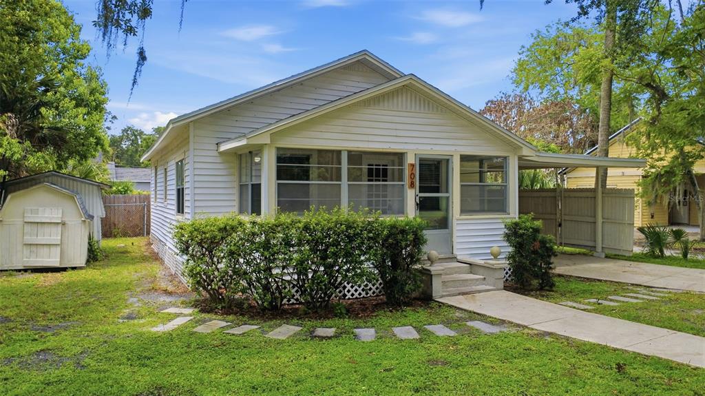 A white, single-story house with a front porch, a carport, and a small storage shed — 708 CELERY AVENUE, SANFORD, FL